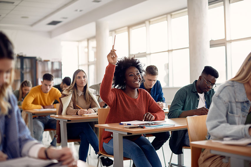 student raising her hand in a classroom